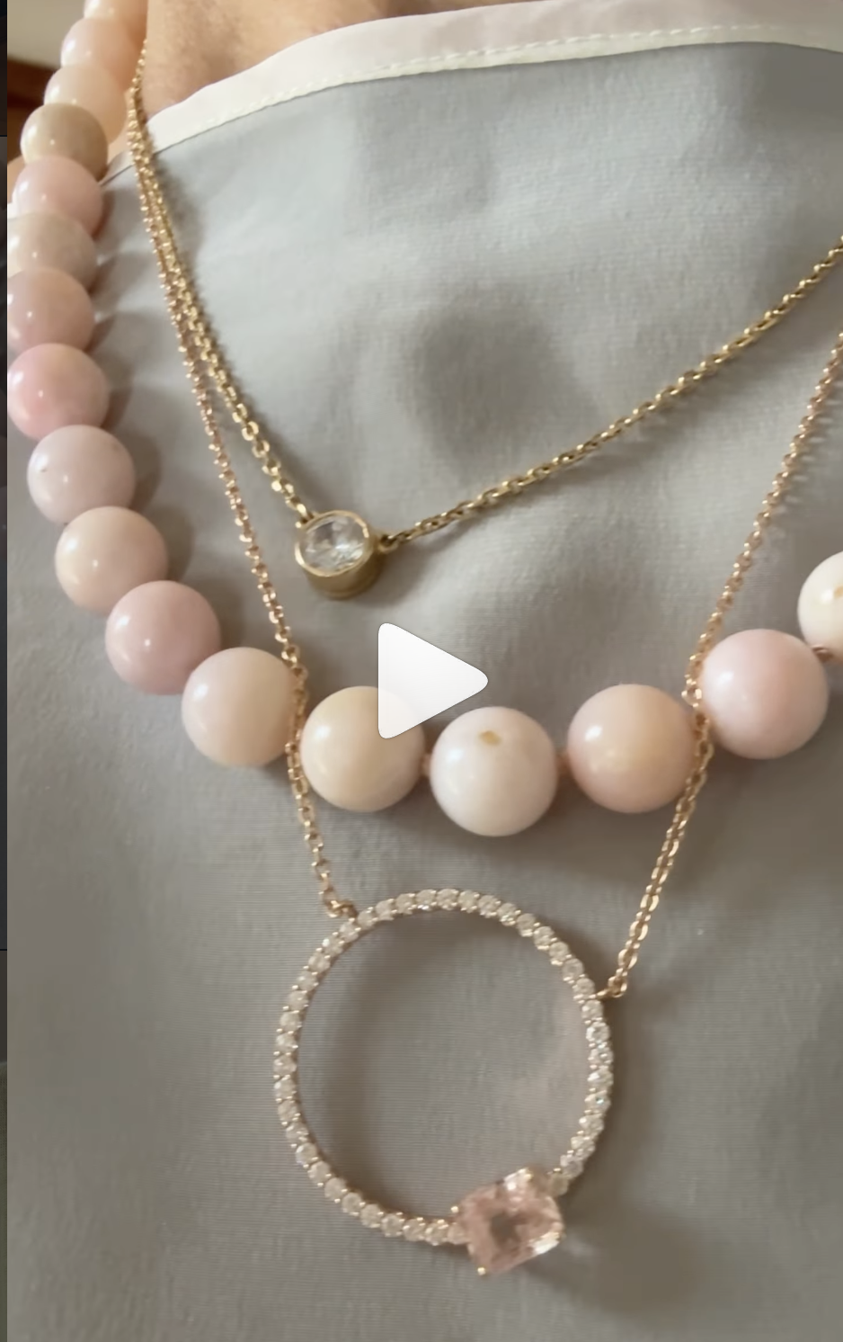 Pale pink beads layered with gemstone pendant necklaces, including an open circle pendant.