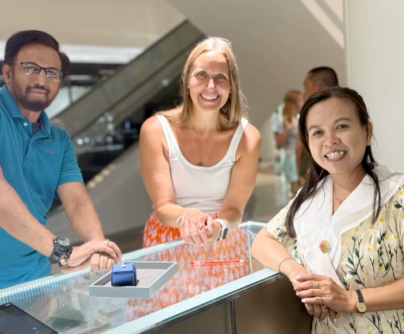 Three people smiling around a gemstone display counter.
