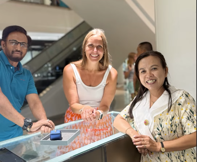 Three people smiling around a gemstone display counter.