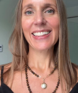 Woman smiling and wearing layered necklaces.