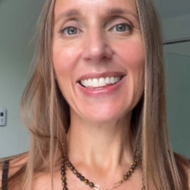 Woman smiling and wearing layered necklaces.