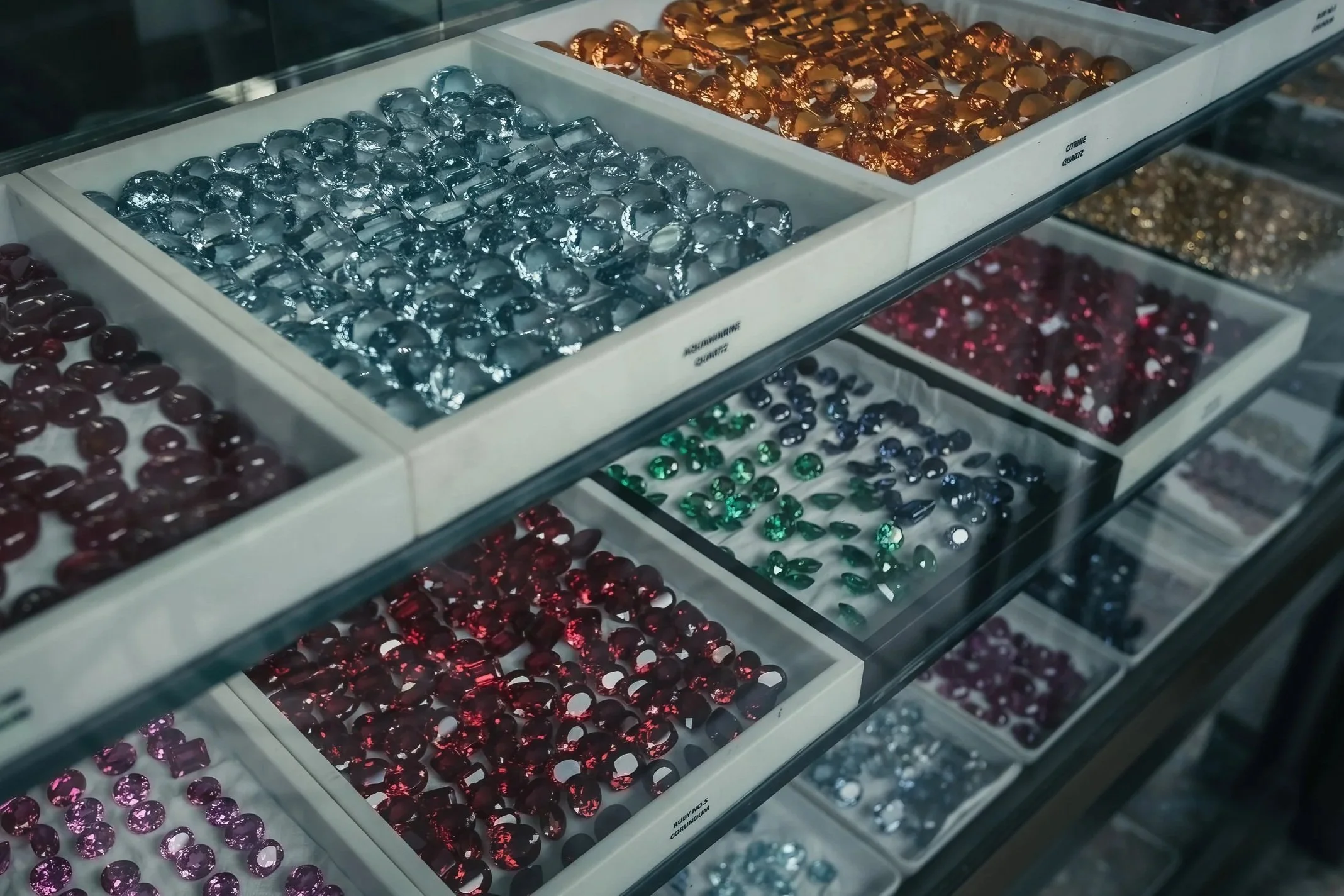 Colorful loose stones arranged in trays at a jewelry counter.