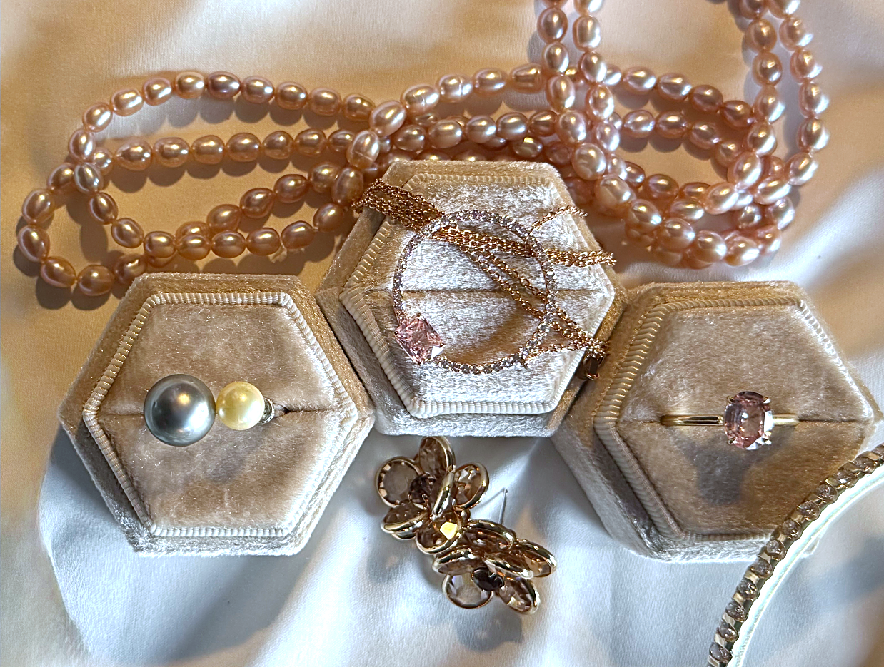 Necklaces and gemstone rings arranged on light fabric with velvet jewelry boxes.