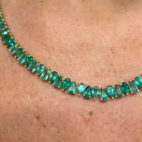 Close-up of a green stone bead necklace worn at the collarbone.