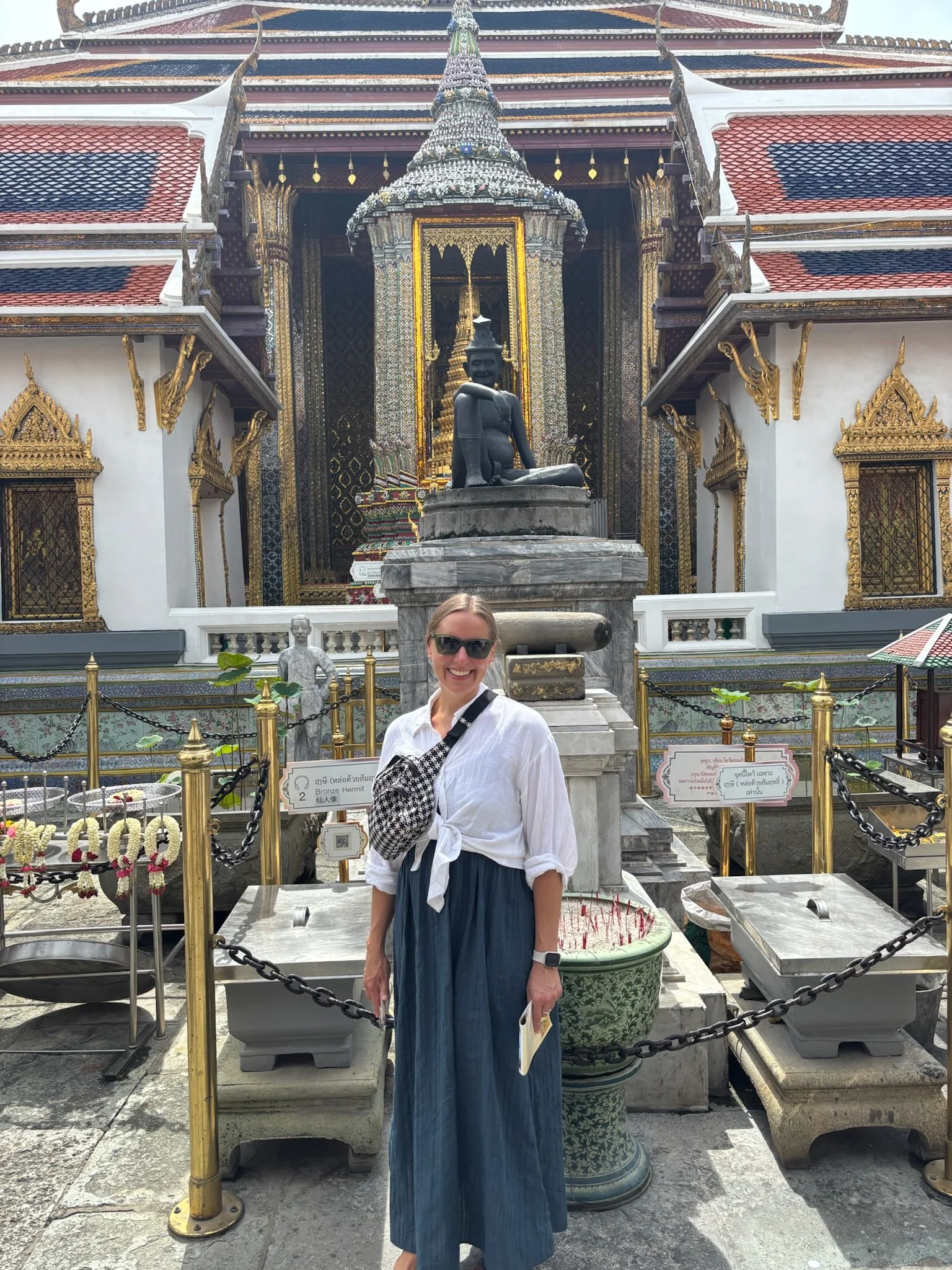 Woman standing in front of an ornate temple shrine.