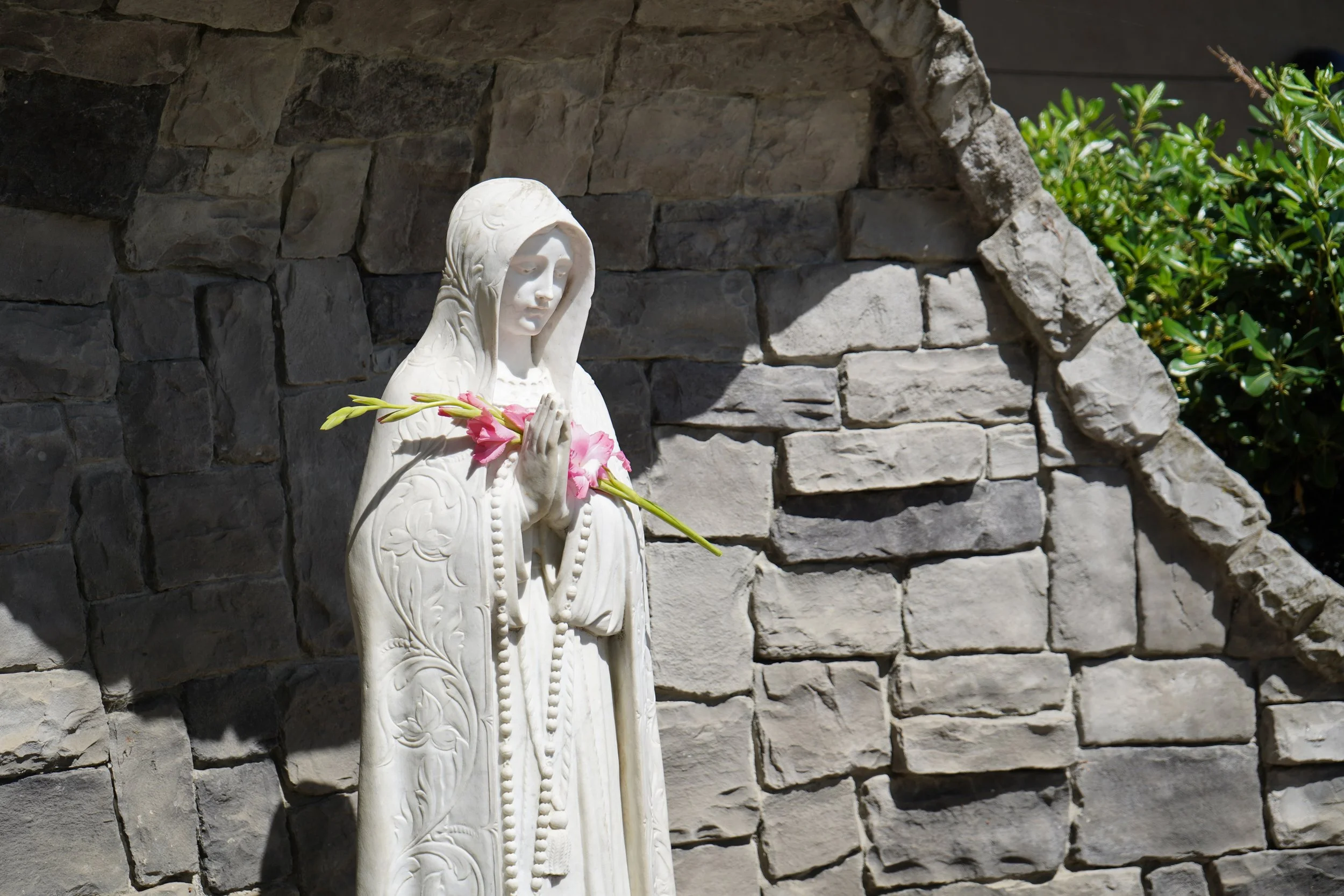Statue of the Virgin Mary holding pink flowers