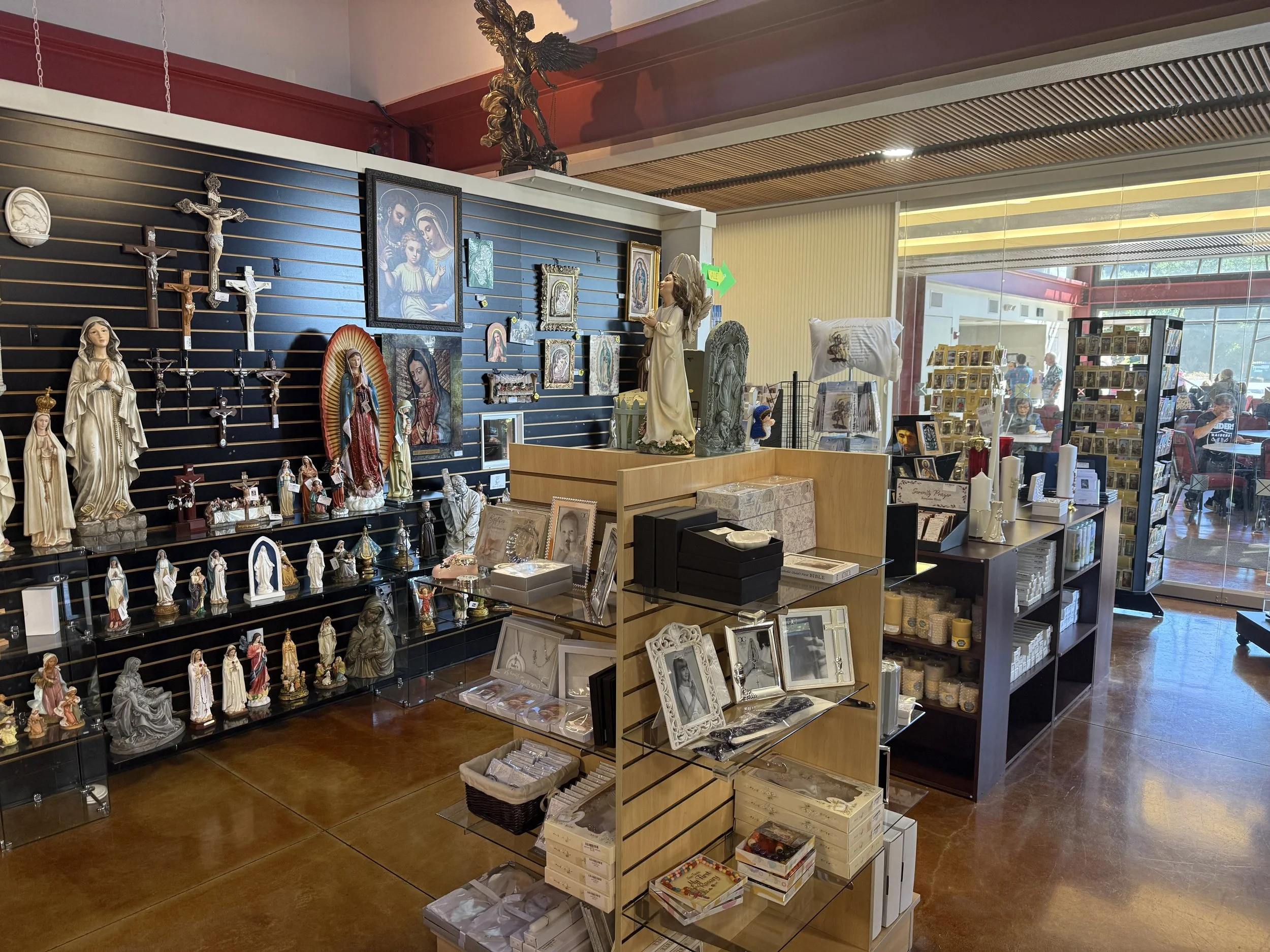 Inside Cathedral Books & Gifts shop at St Eugene Cathedral with display shelves filled with Christian statues, crosses, framed religious images, candles, and greeting cards.