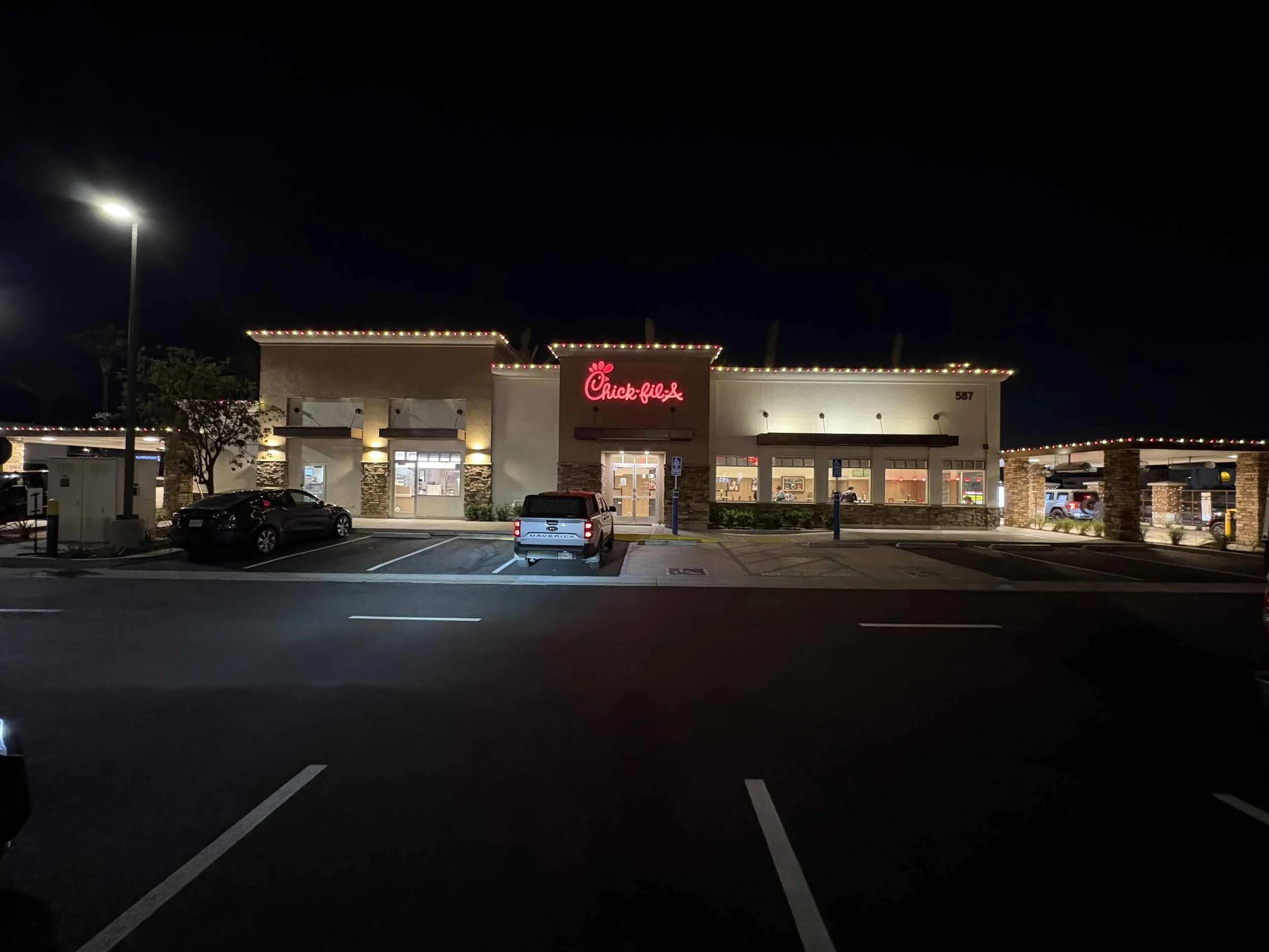 Commercial storefront decorated with red and white string lights along the roofline at night. Orlando Commercial Christmas Lighting, Winter Park Holiday Lighting, Windermere Christmas Light Installation Near Me