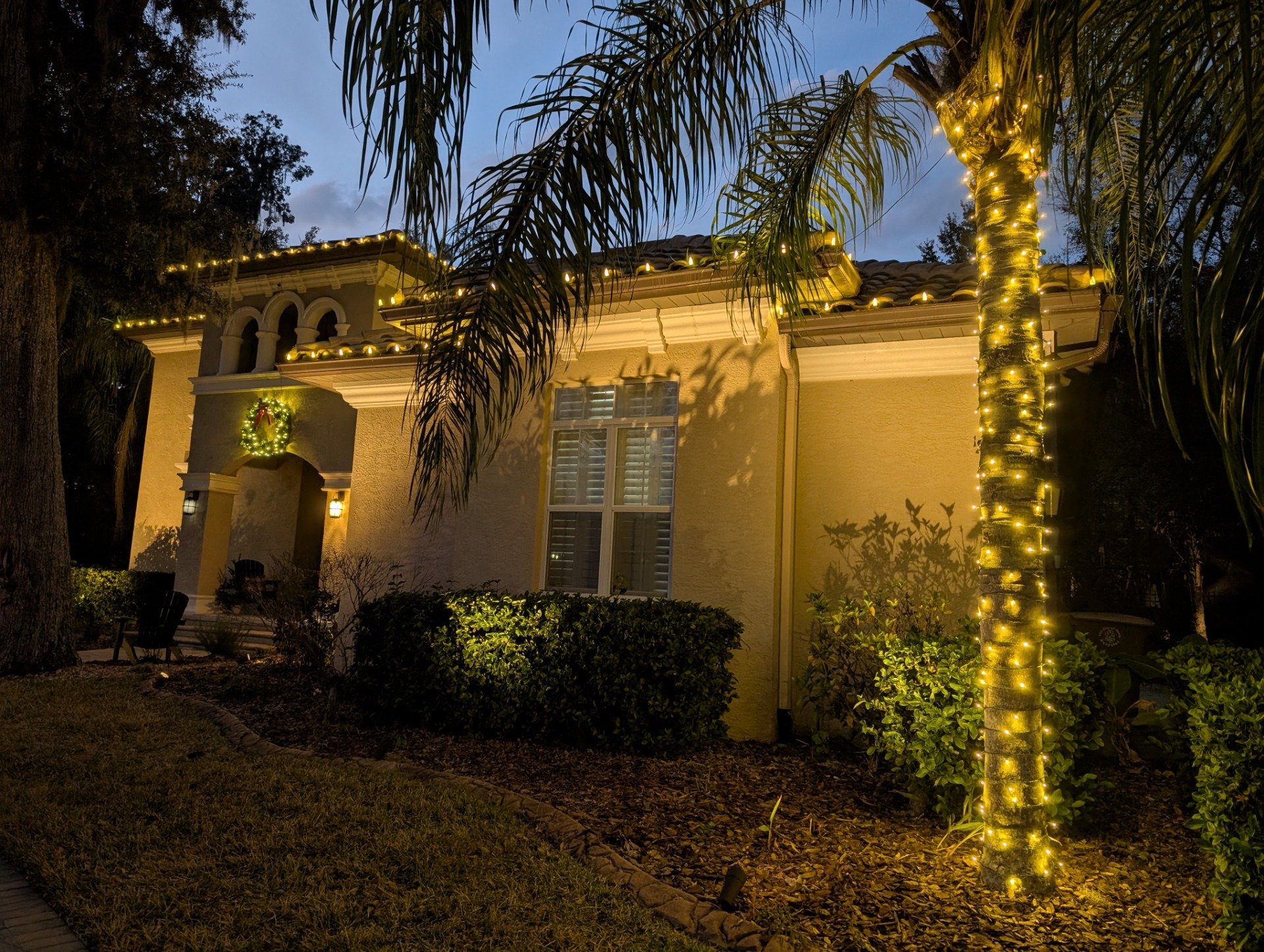 Christmas light installation with a wreath on the front door of an Orlando home at dusk