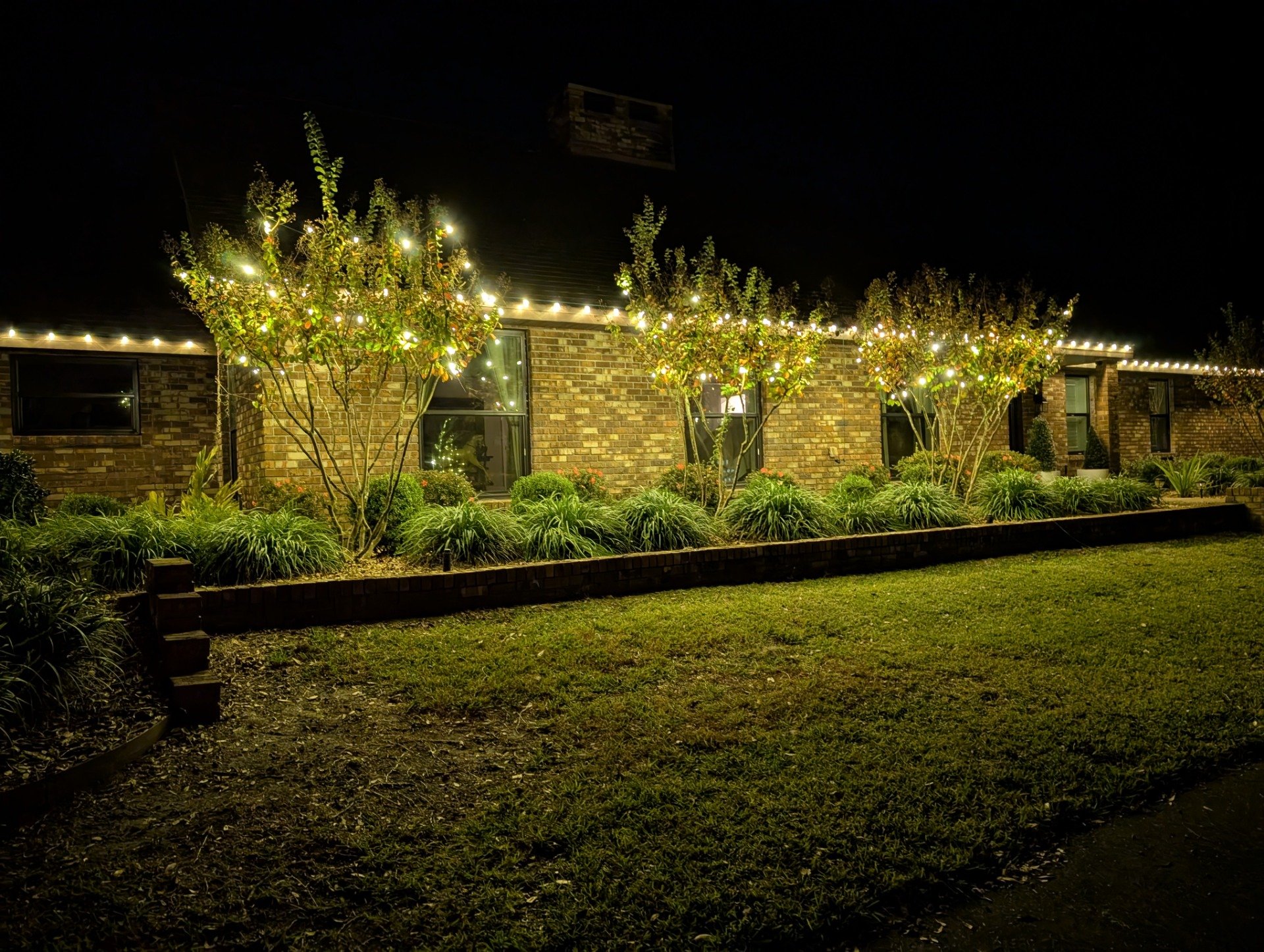 Christmas light installation on a brick home in Windermere, roofline and trees lit up