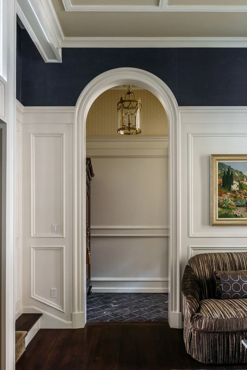 Interior view of a home with a decorative archway, painted walls, framed artwork, and a vaulted ceiling with a hanging lantern light fixture.