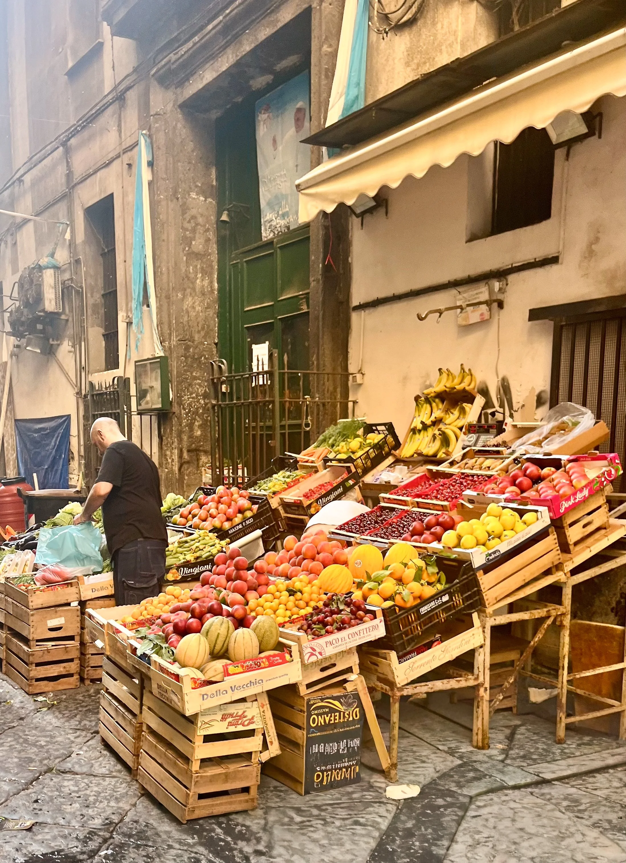 A typical fruttivendolo (greengrocers) in Napoli's Spanish Quarter, selling various fresh fruits including apples, bananas, melons, and peaches. Some say the Napoli is the real Italy.
