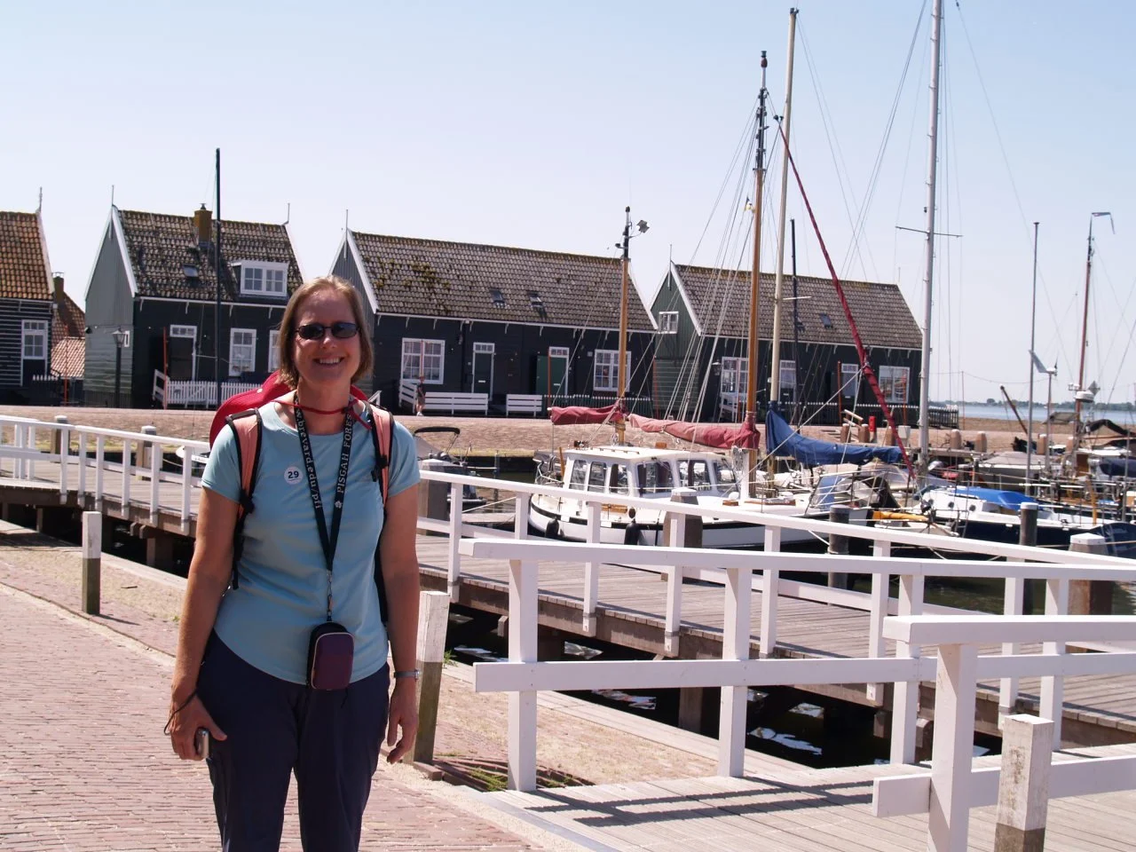 Amy standing on a sunny dock surrounded by sailboats