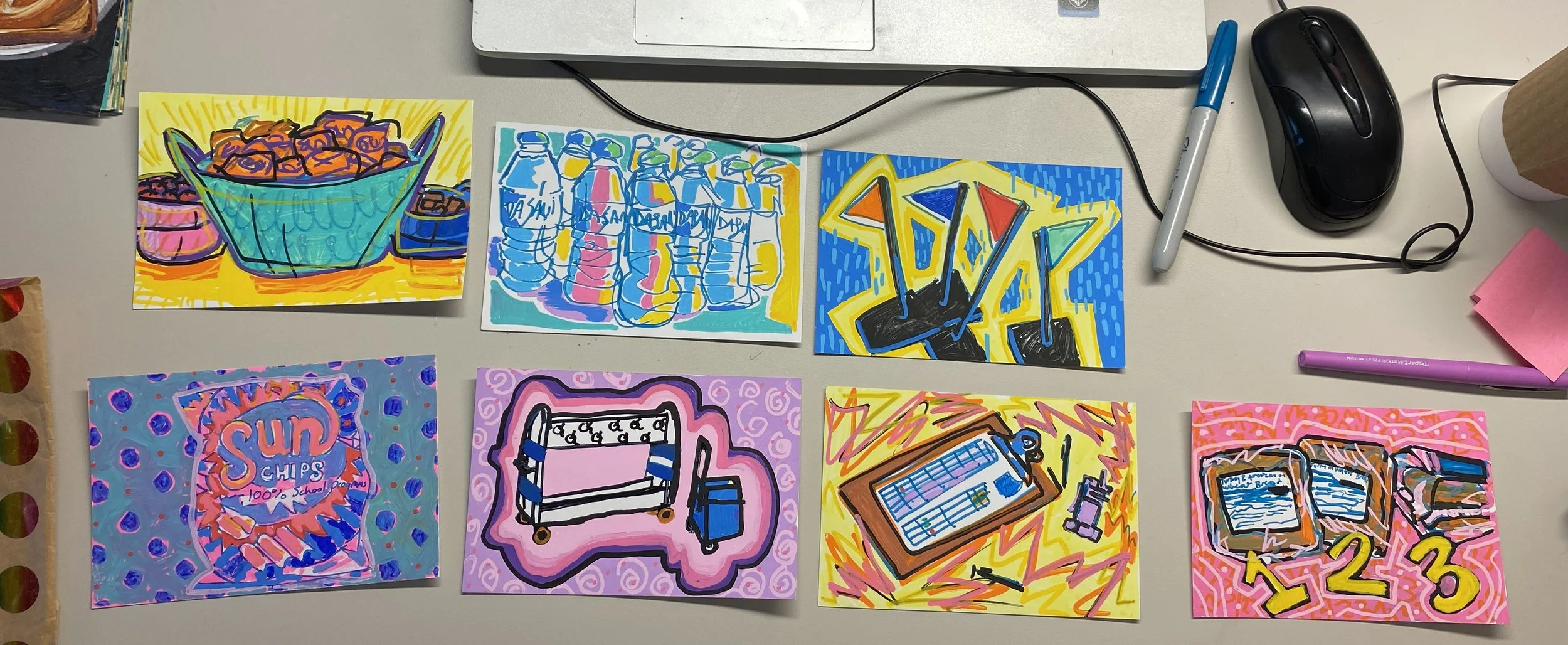 Set of colorful, illustrated cards on a desk, featuring drawings of a bowl of chips, bottles, a skateboard, lottery tickets, and other objects.