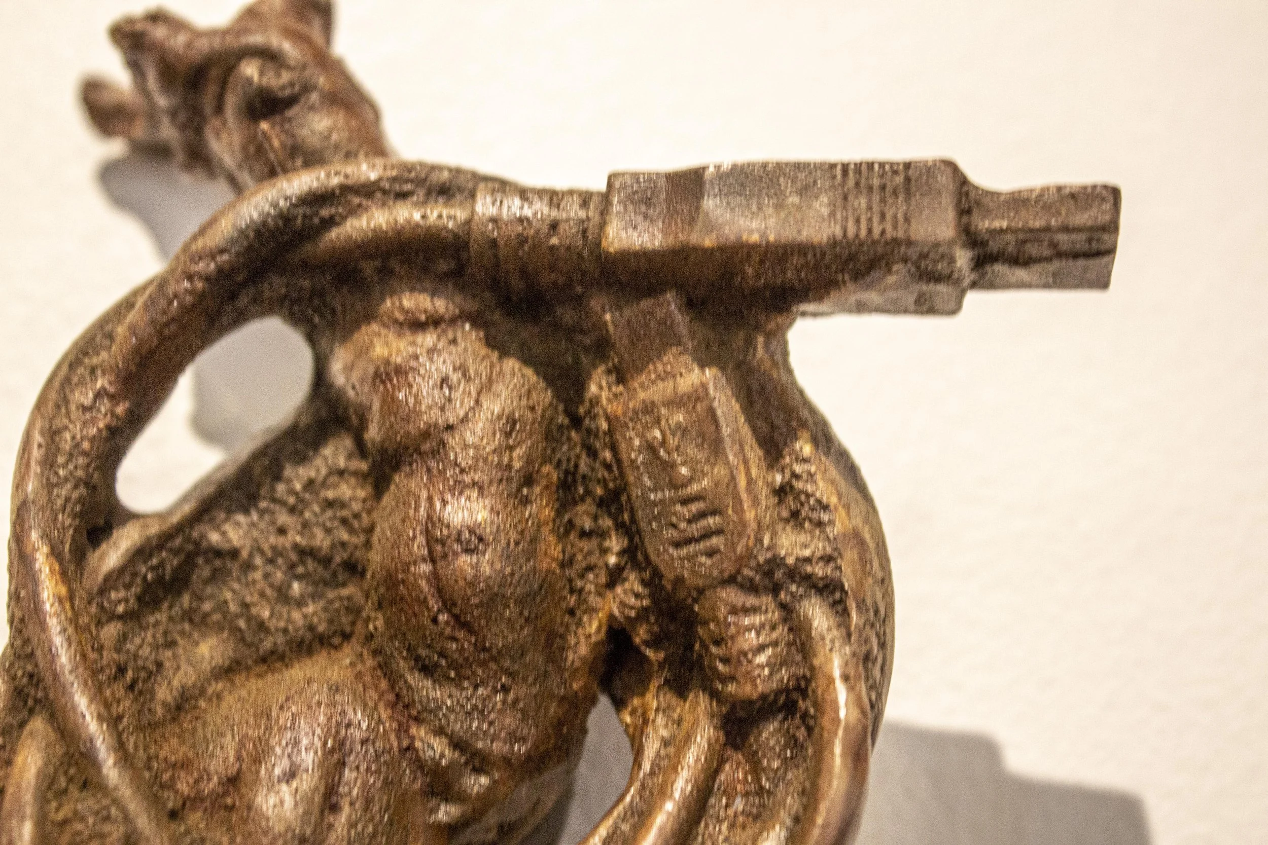 Close-up of a detailed cast iron sculpture of a root wrapped in an electronic charging cord. 