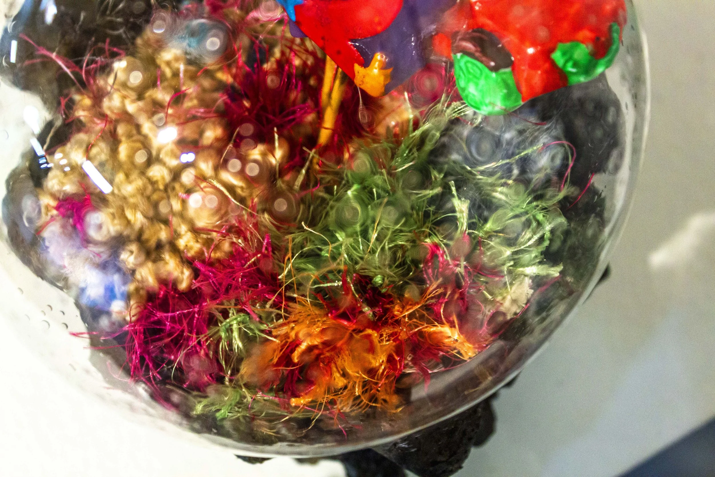 Close-up of a glass bowl filled with decorative colorful shredded paper and small plastic toys