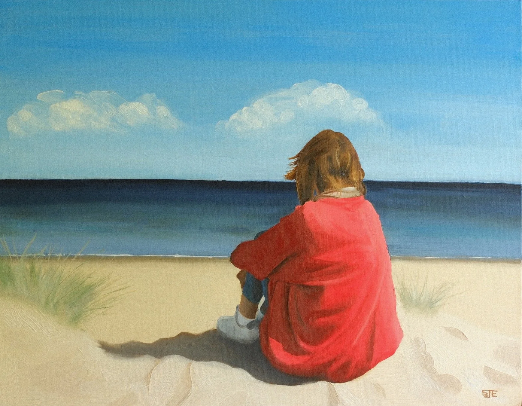 Juliana sitting on a beach in Northumberland facing the sea
