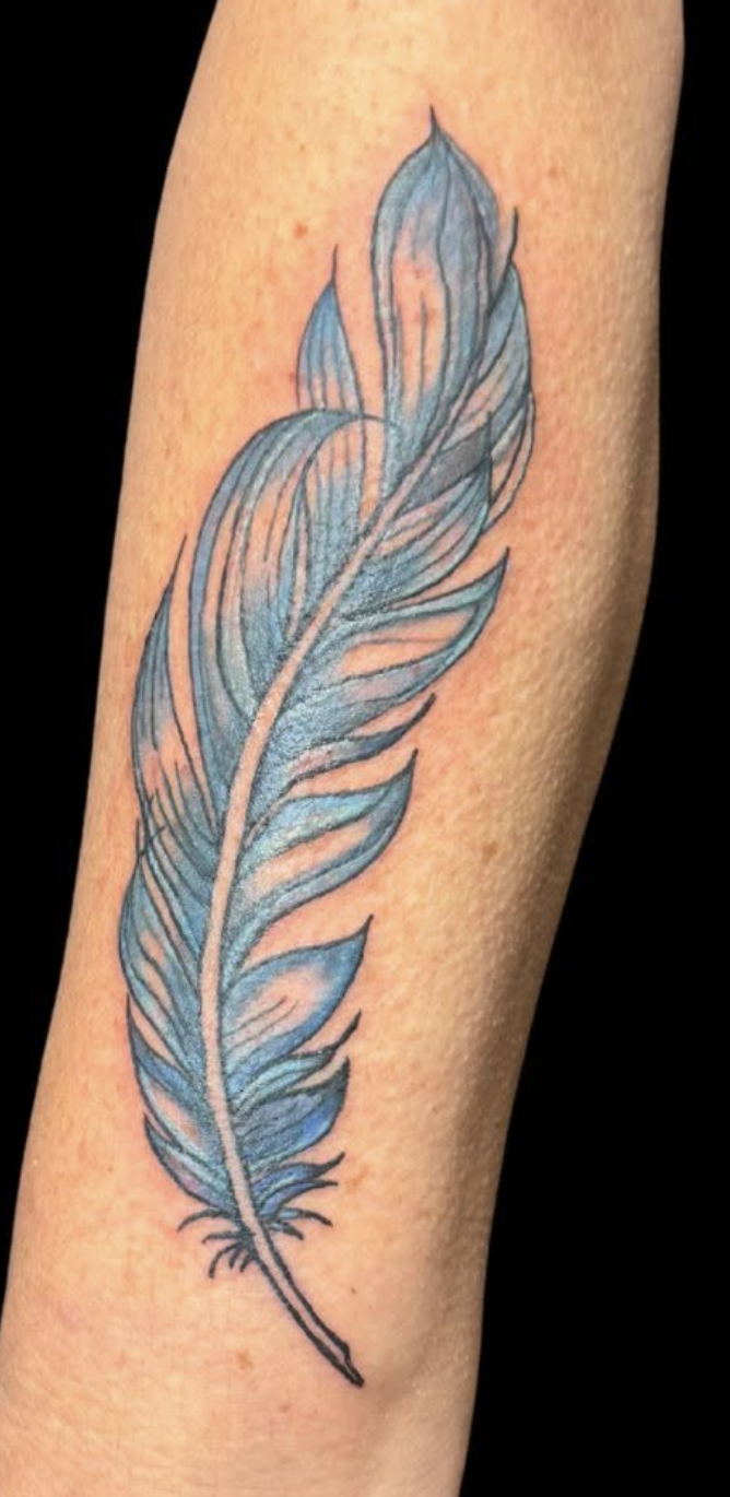 Blue and black feather tattoo on skin.