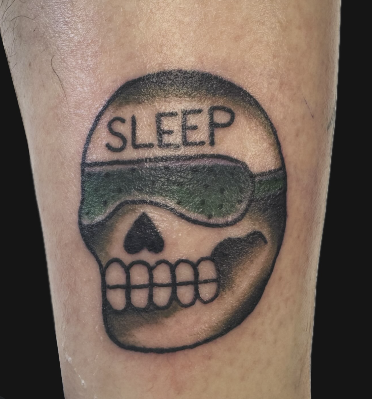 A tattoo of a skull wearing sleep goggles with the word 'SLEEP' on it.