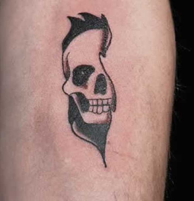 Tattoo of a skull with a stylized, dripping design on skin.