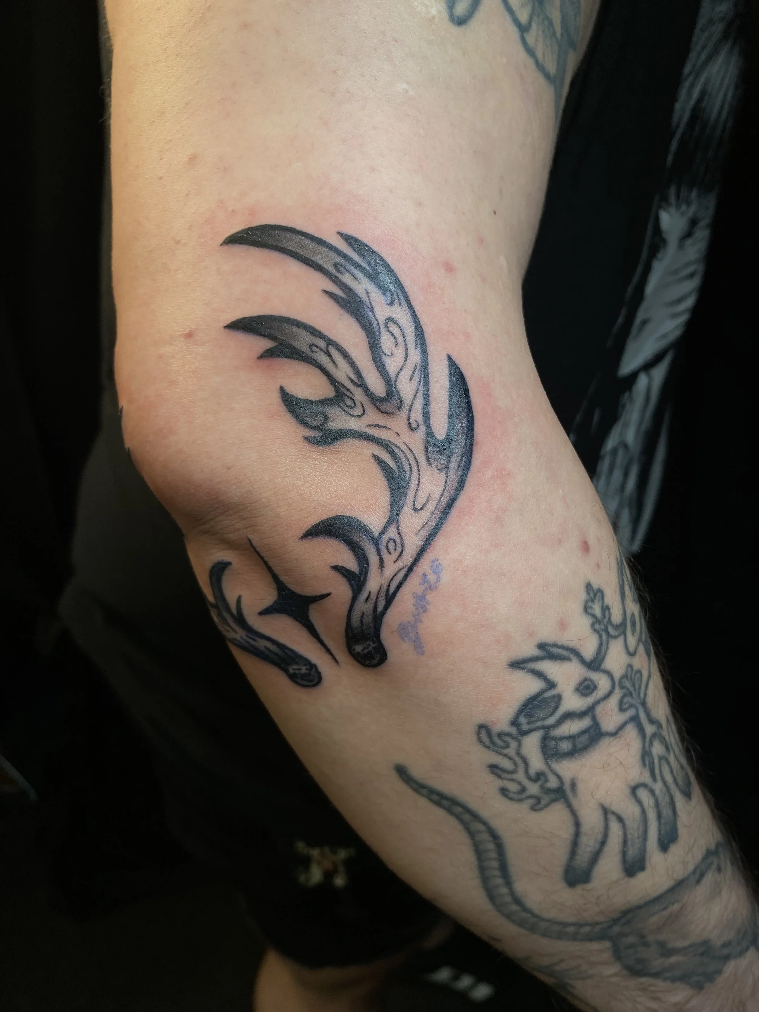 A tattoo of a stylized dolphin on a person's arm.