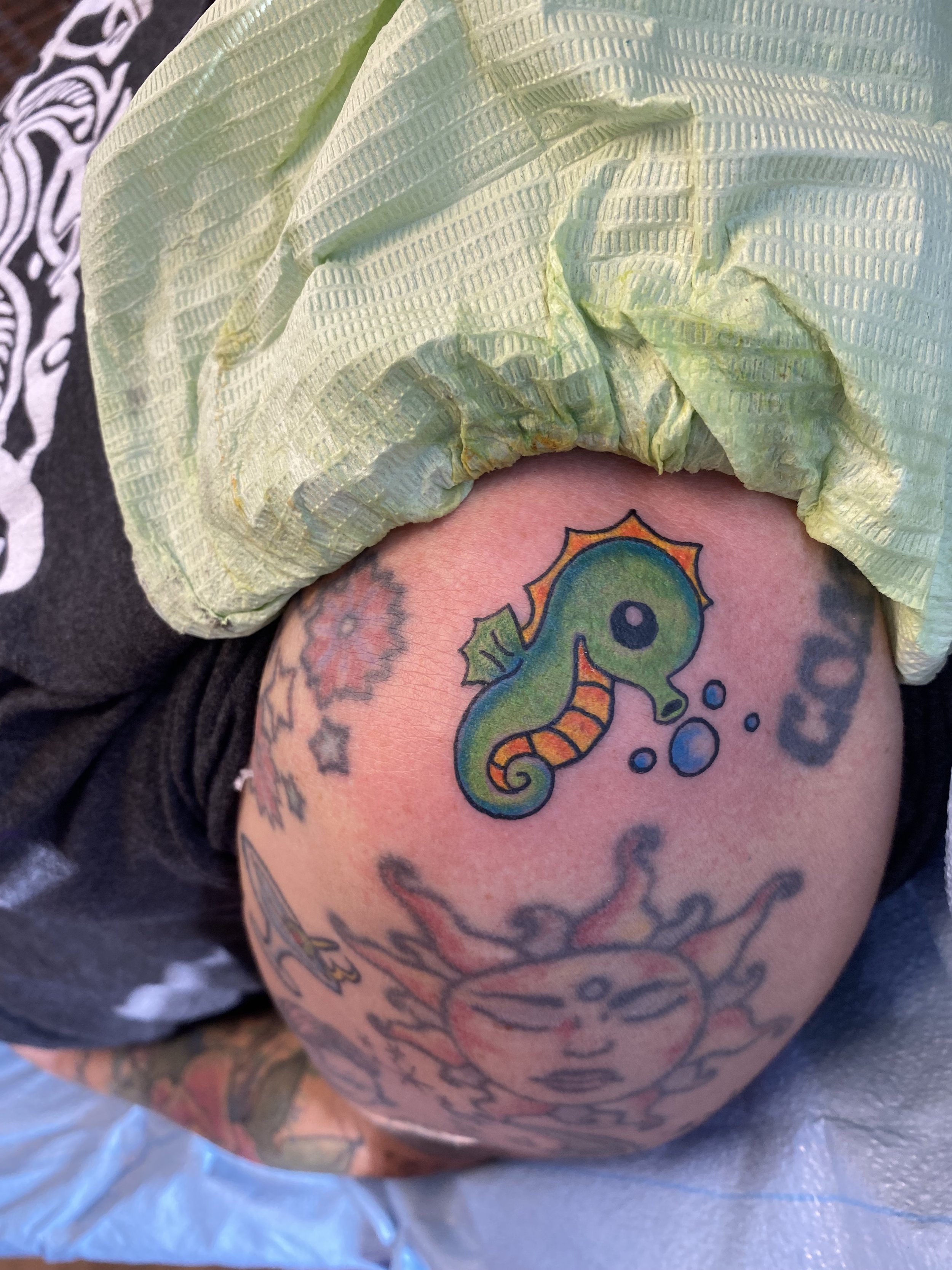 A tattoo of a colorful seahorse on a person's upper arm.