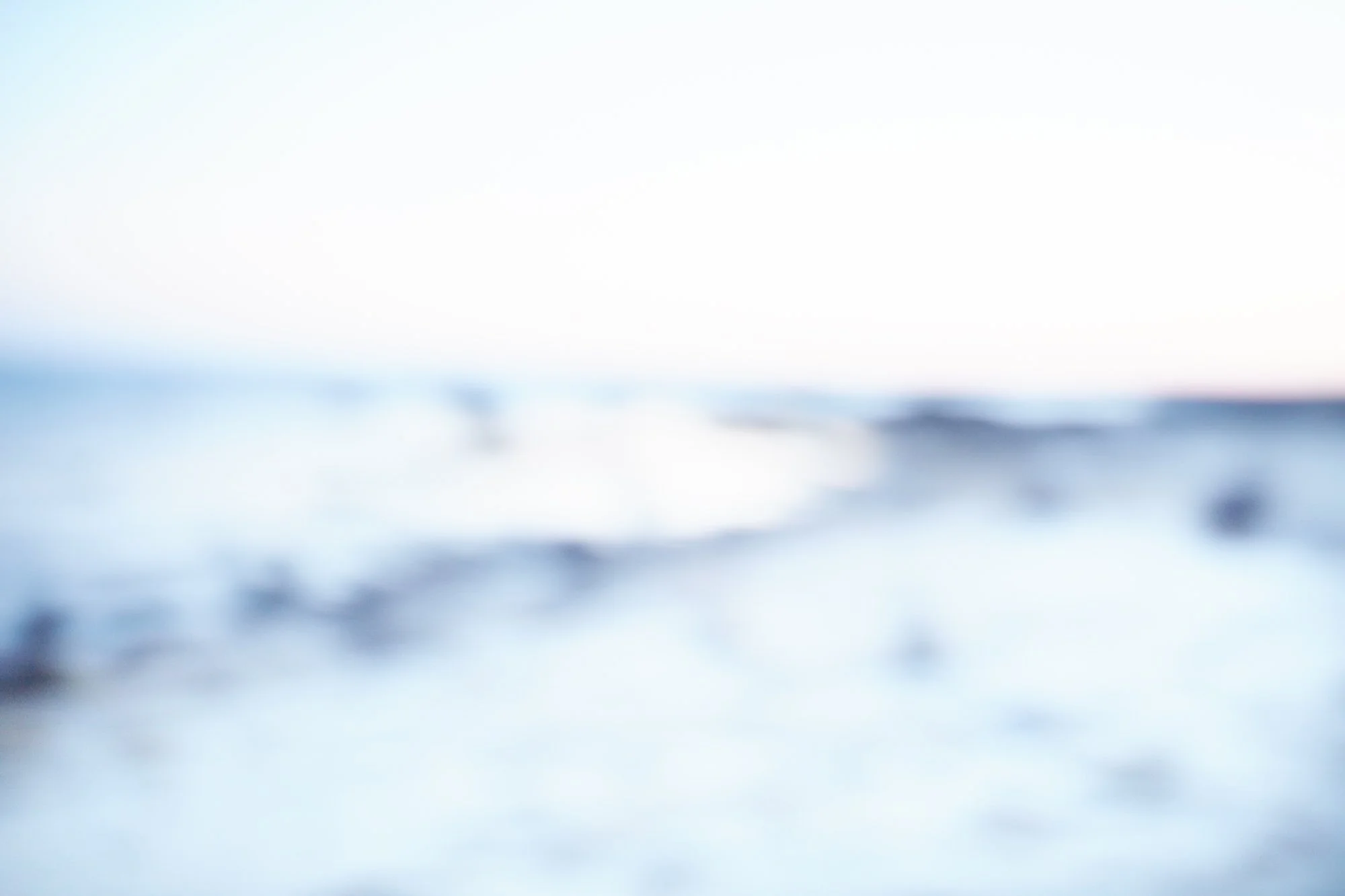 Blurred photo of a seascape with ocean waves and a distant horizon, light sky.