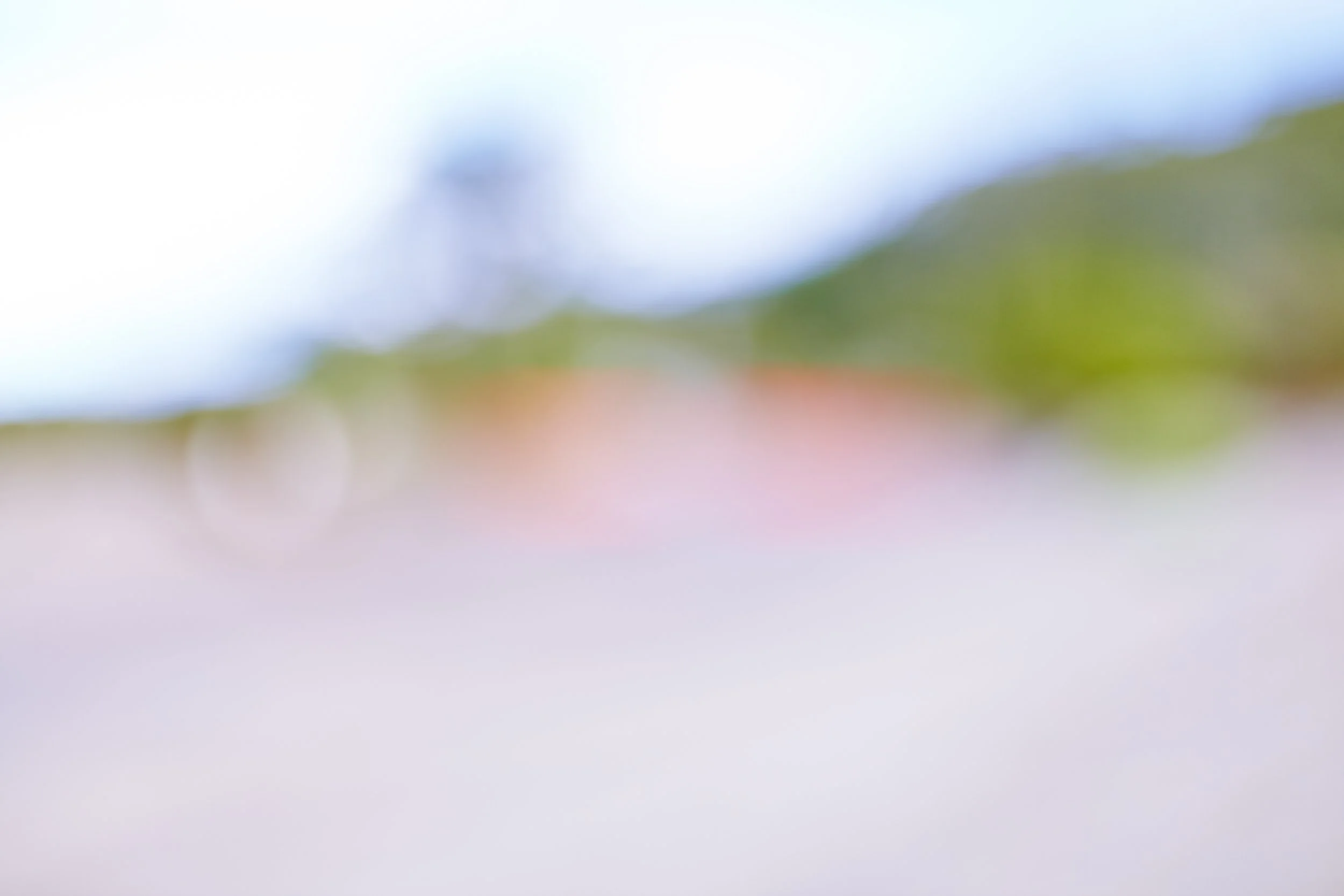 The image appears blurry and abstract, with a gradient of colors including blue, green, pink, and white, but no discernible objects or details can be identified.