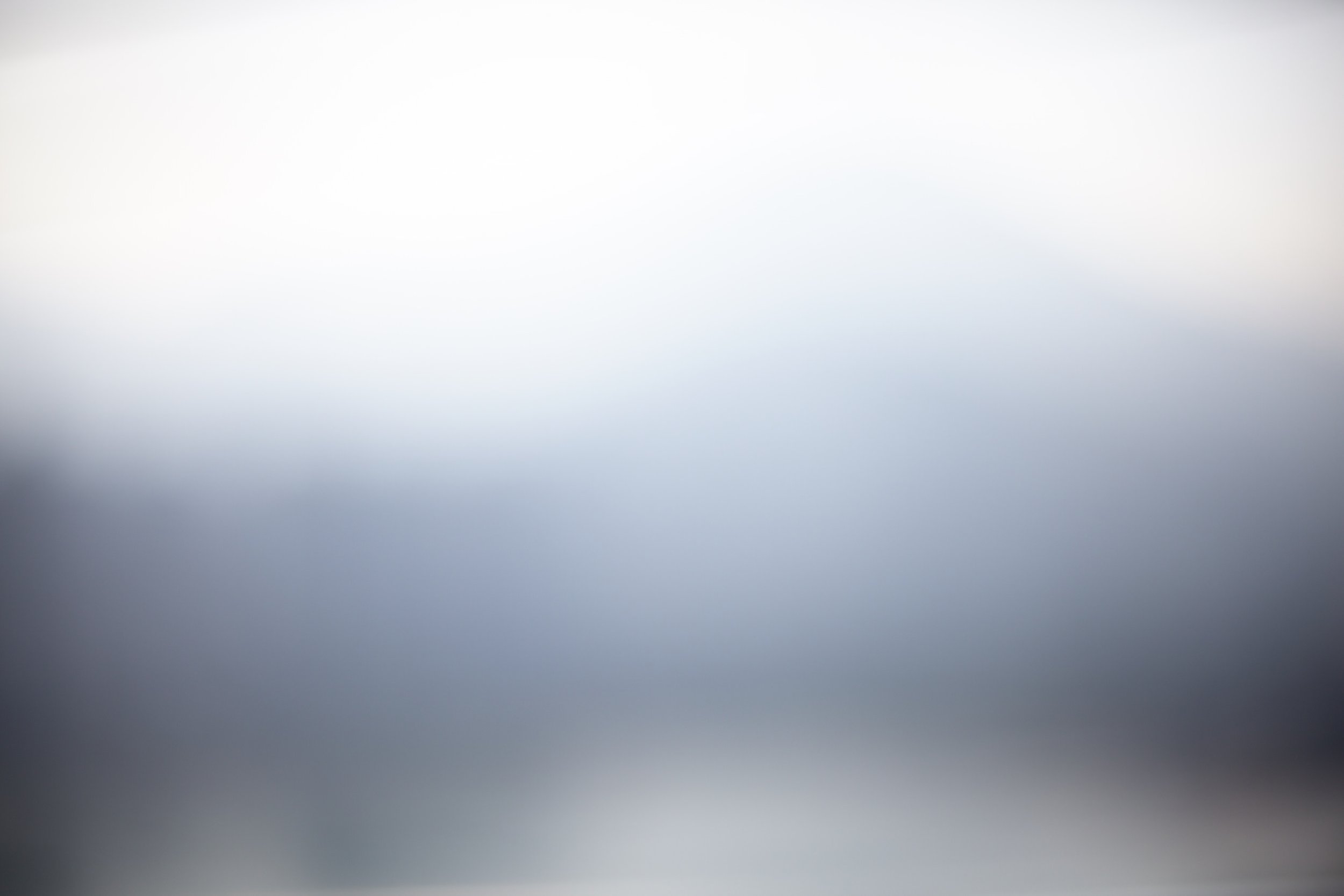 An abstract image with a gradient of light to dark shades, transitioning from pale gray at the top to darker gray at the bottom.