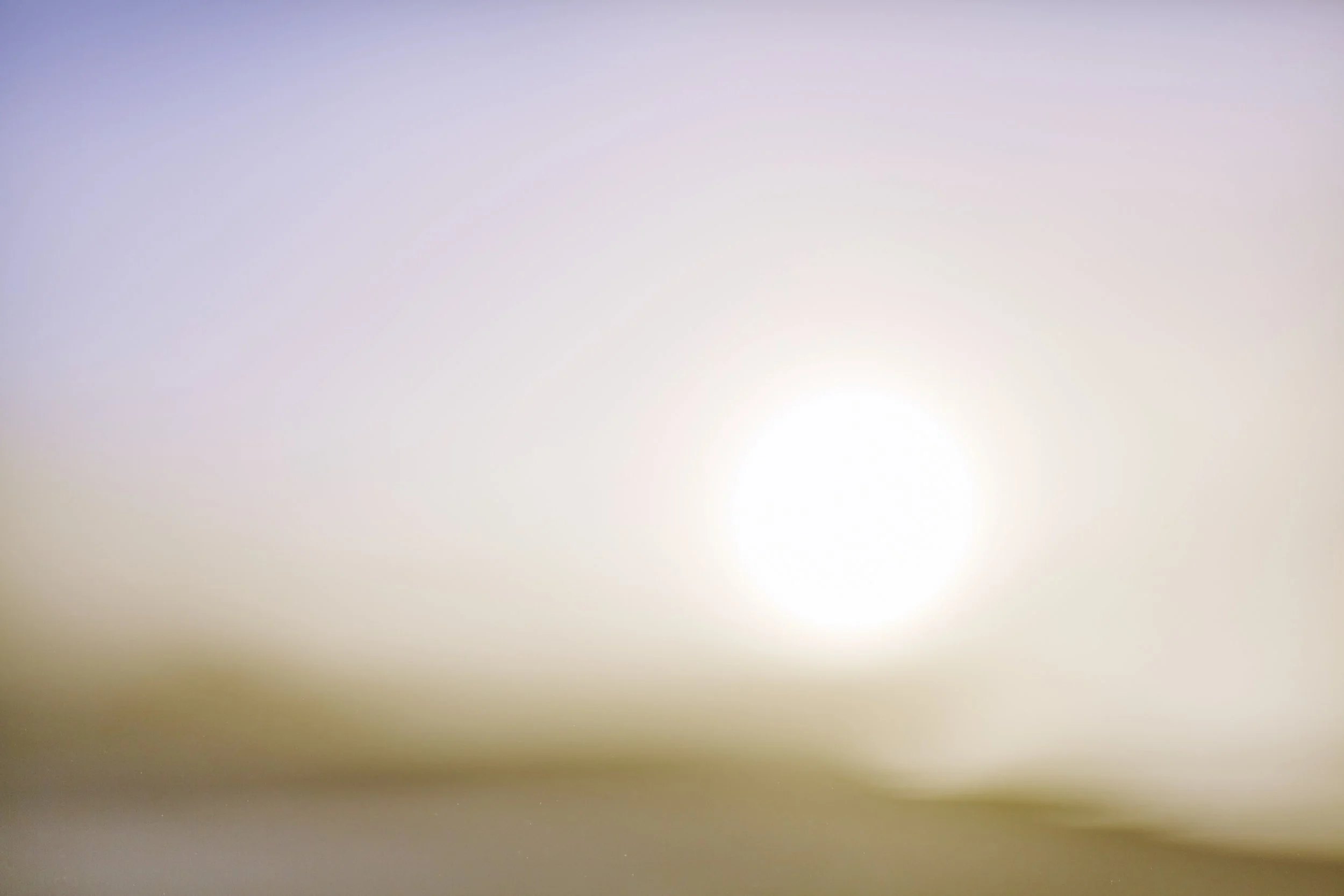 An abstract image with a bright focal point near the bottom right, radiating light and subtle color gradients in shades of purple, pink, and beige.
