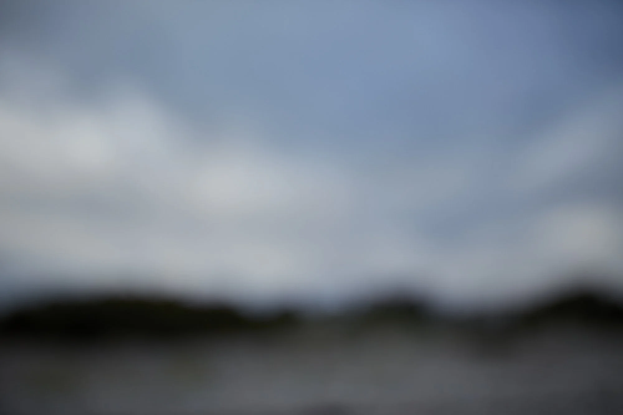 Blurry overcast sky with dark clouds and a faint horizon line at the bottom.