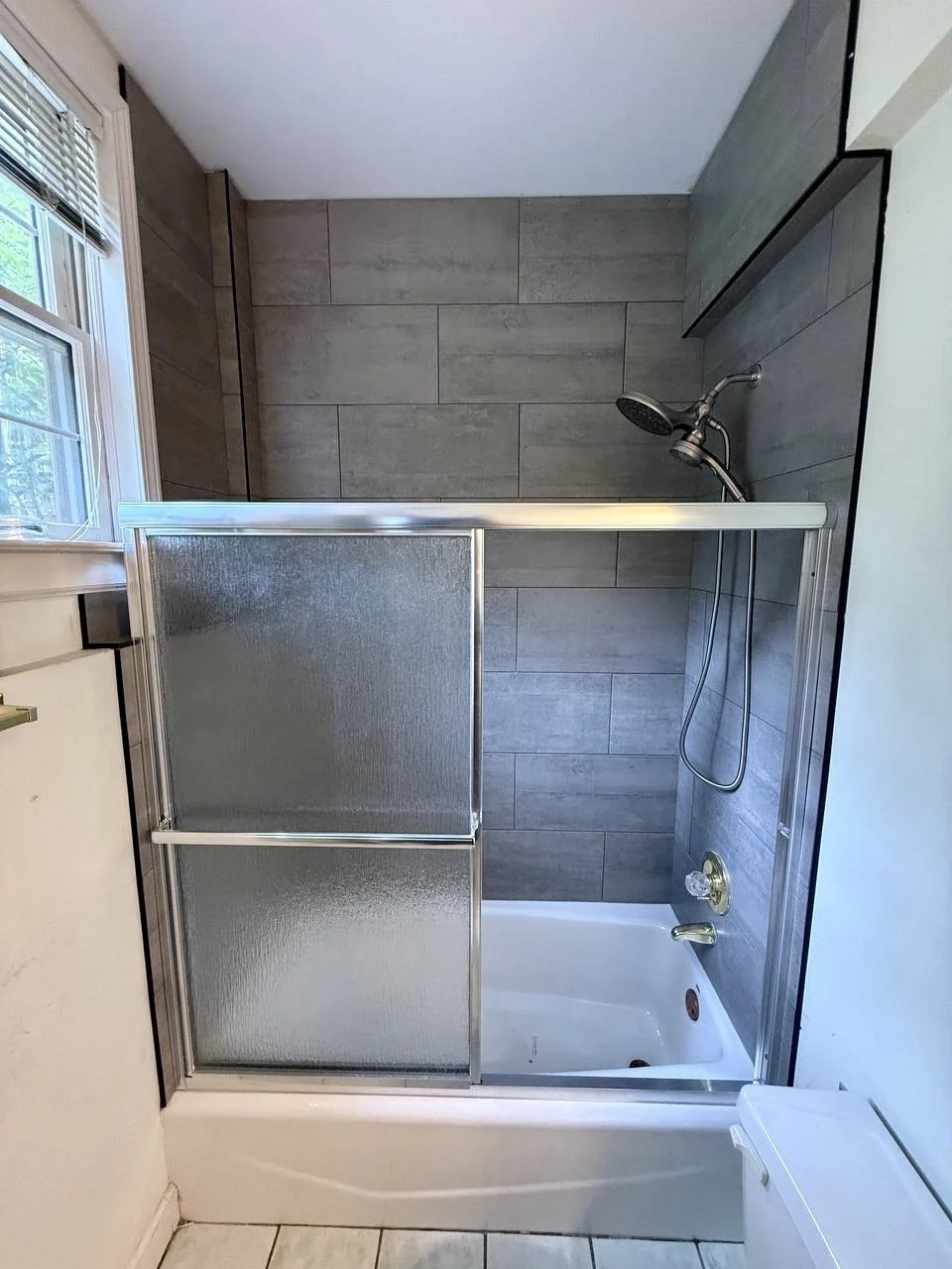 Tub and shower surround upgraded with large-format gray tile and a clean, modern layout.