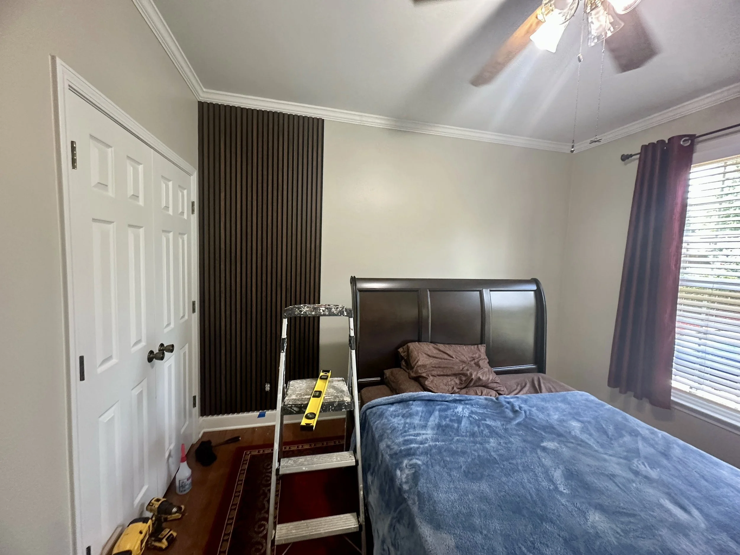 Custom wood slat accent wall installation in progress, adding warmth, texture, and a modern architectural detail to the bedroom.