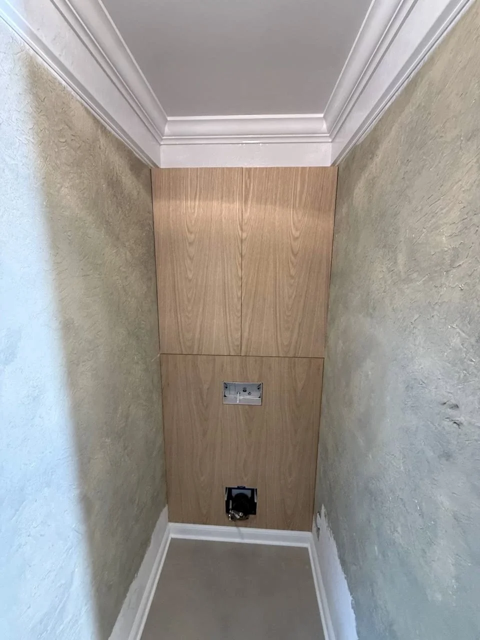 Custom wood-look wall panels provide concealed storage and access while maintaining a clean, streamlined appearance.