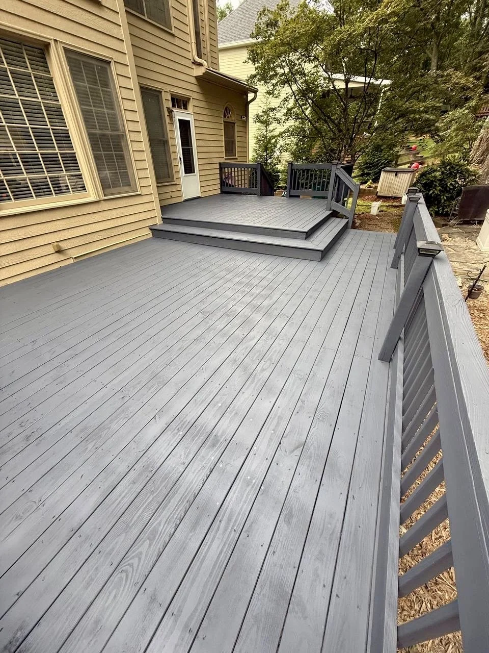 Spacious backyard deck refinished in a modern gray tone, refreshing the walking surface, steps, and railings.