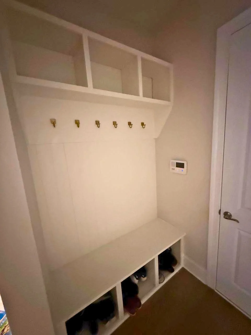 Built-in mudroom storage featuring a bench, shoe cubbies, wall hooks, and overhead compartments for a clean, functional entryway.