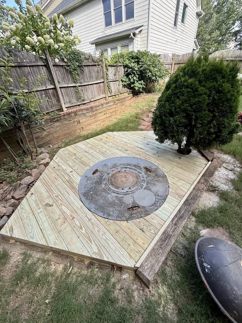 Pressure-treated wood platform constructed around an existing fire pit to create a cleaner, more functional backyard gathering area.