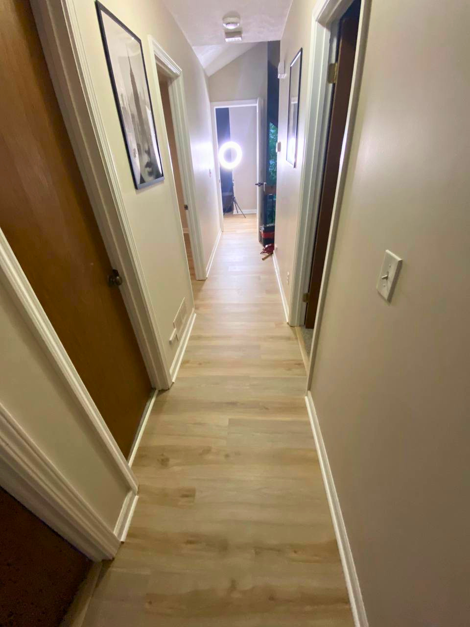 Light-toned wood flooring installed throughout the hallway for a bright, modern update.