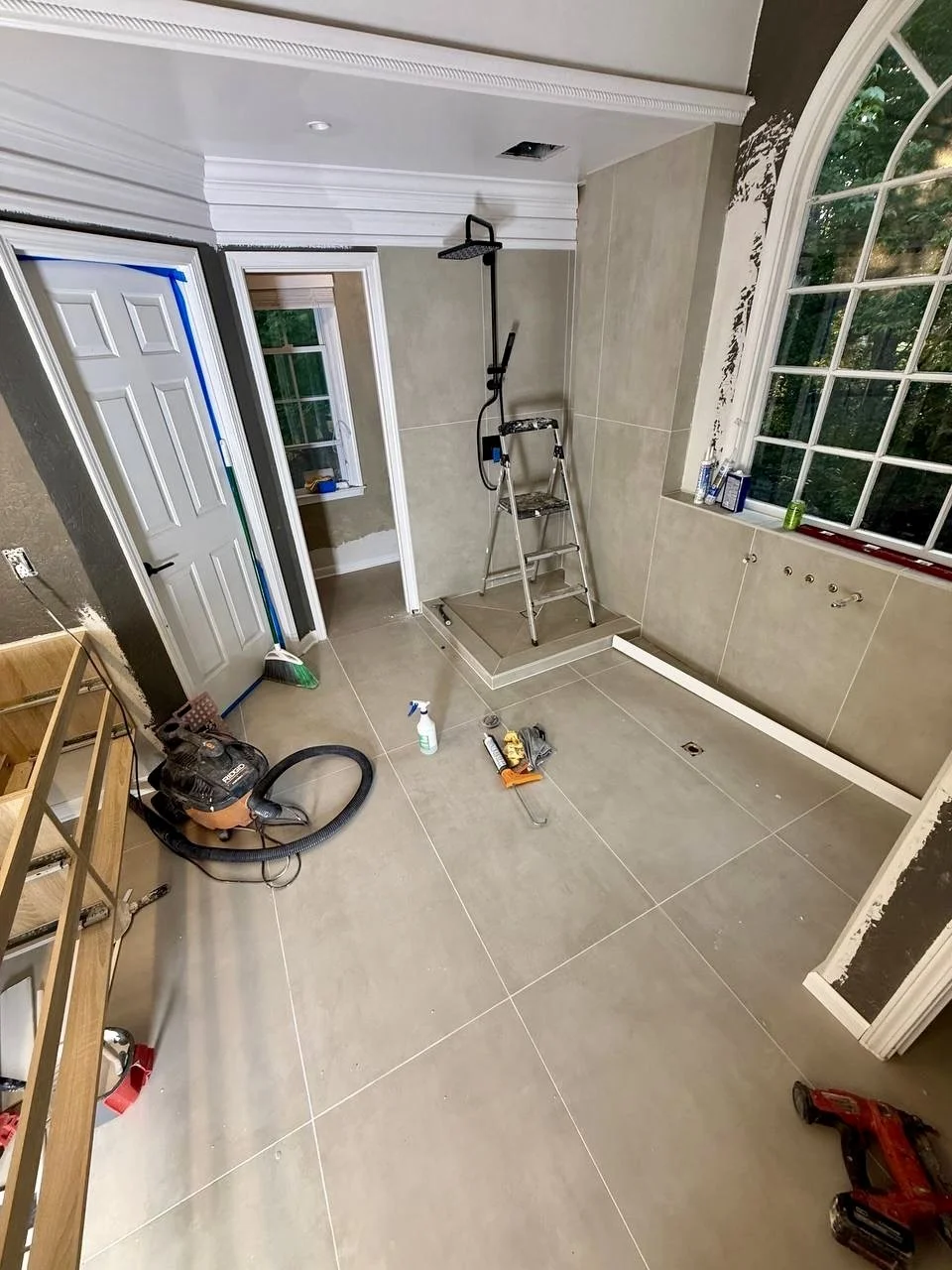 Bathroom renovation in progress featuring large-format tile flooring and walls with a modern walk-in shower.