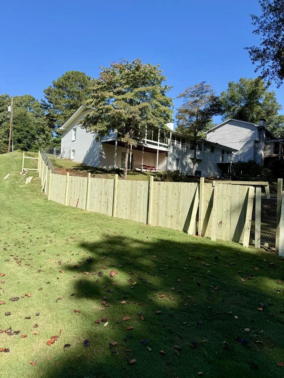 Long-run wood privacy fence installation designed to follow the property’s slope while providing added security and privacy.