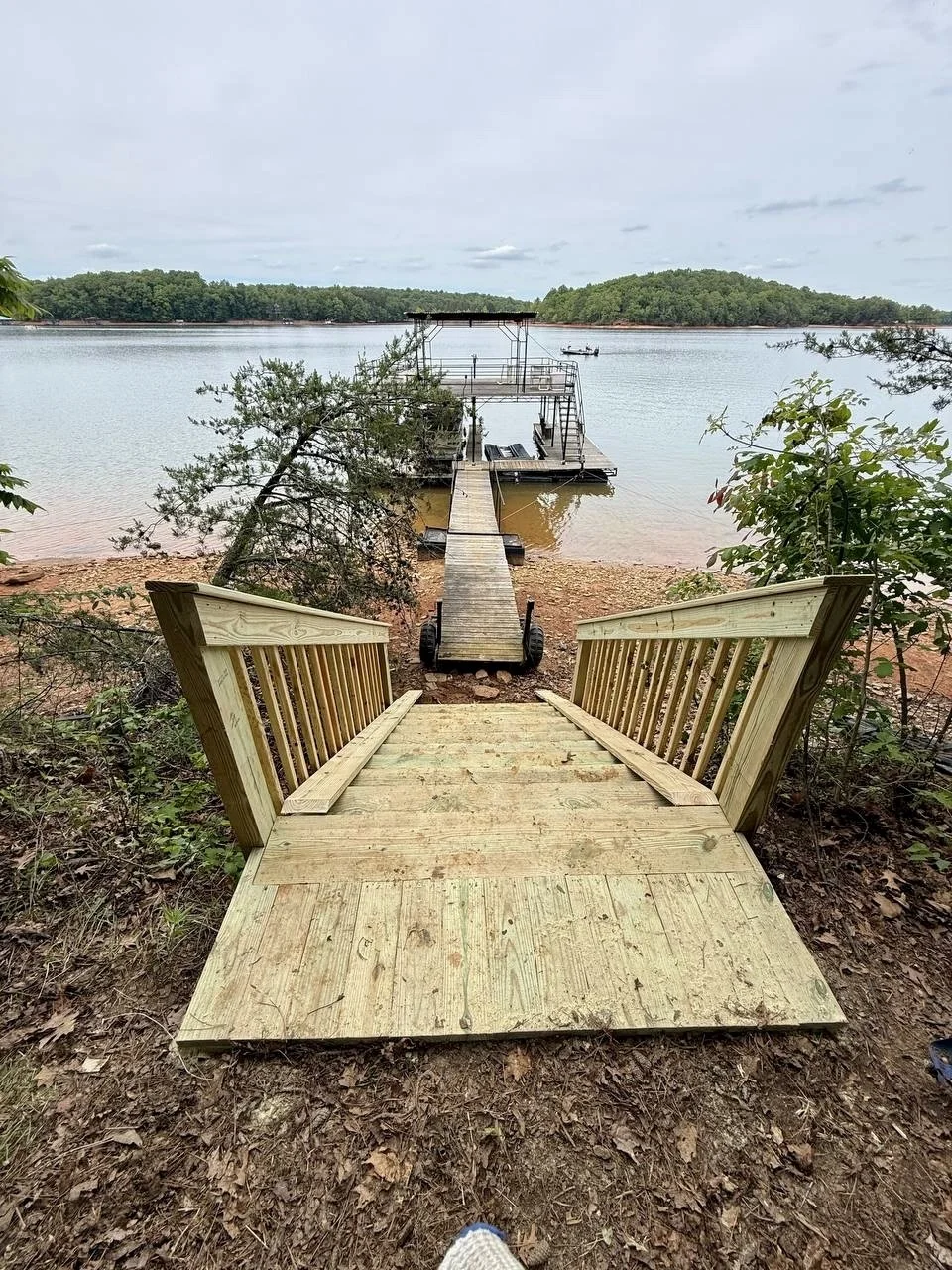 New pressure-treated wood landing, stairs, and railings built to provide safer, easier access down a steep slope to the dock.