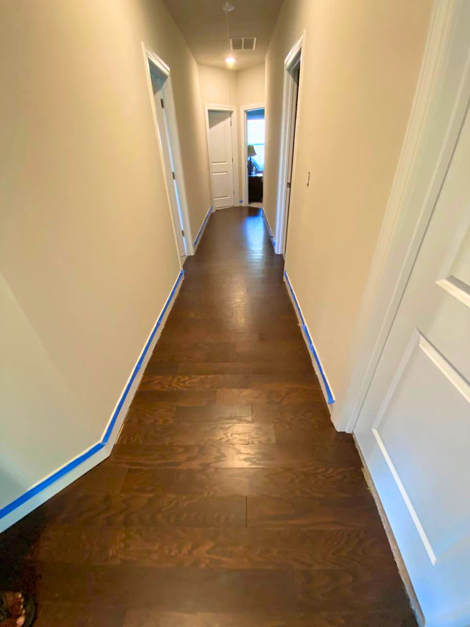 Newly installed dark hardwood flooring creates a polished, continuous look throughout the hallway.
