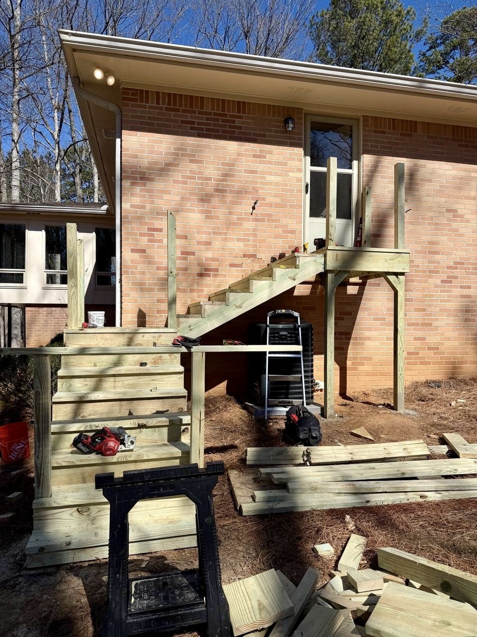 Progress view showing the new landing, structural posts, stair stringers, and steps during construction.
