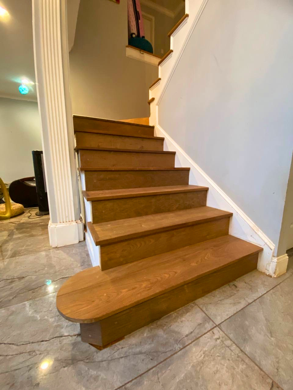 New hardwood treads and risers being fitted over the prepared staircase for a complete wood finish.