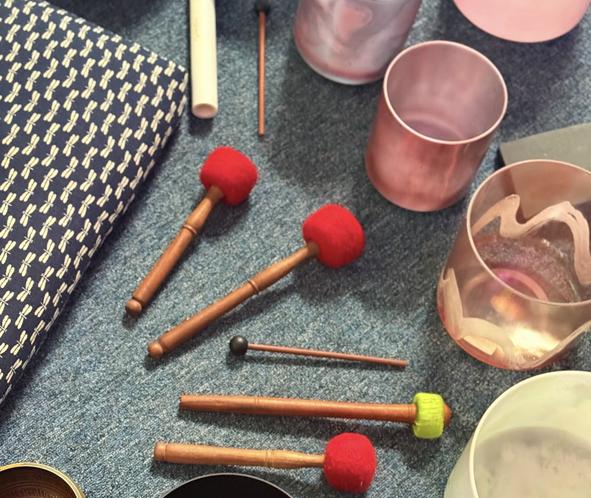 Assorted drinking glasses and musical percussion instruments on a textured surface.