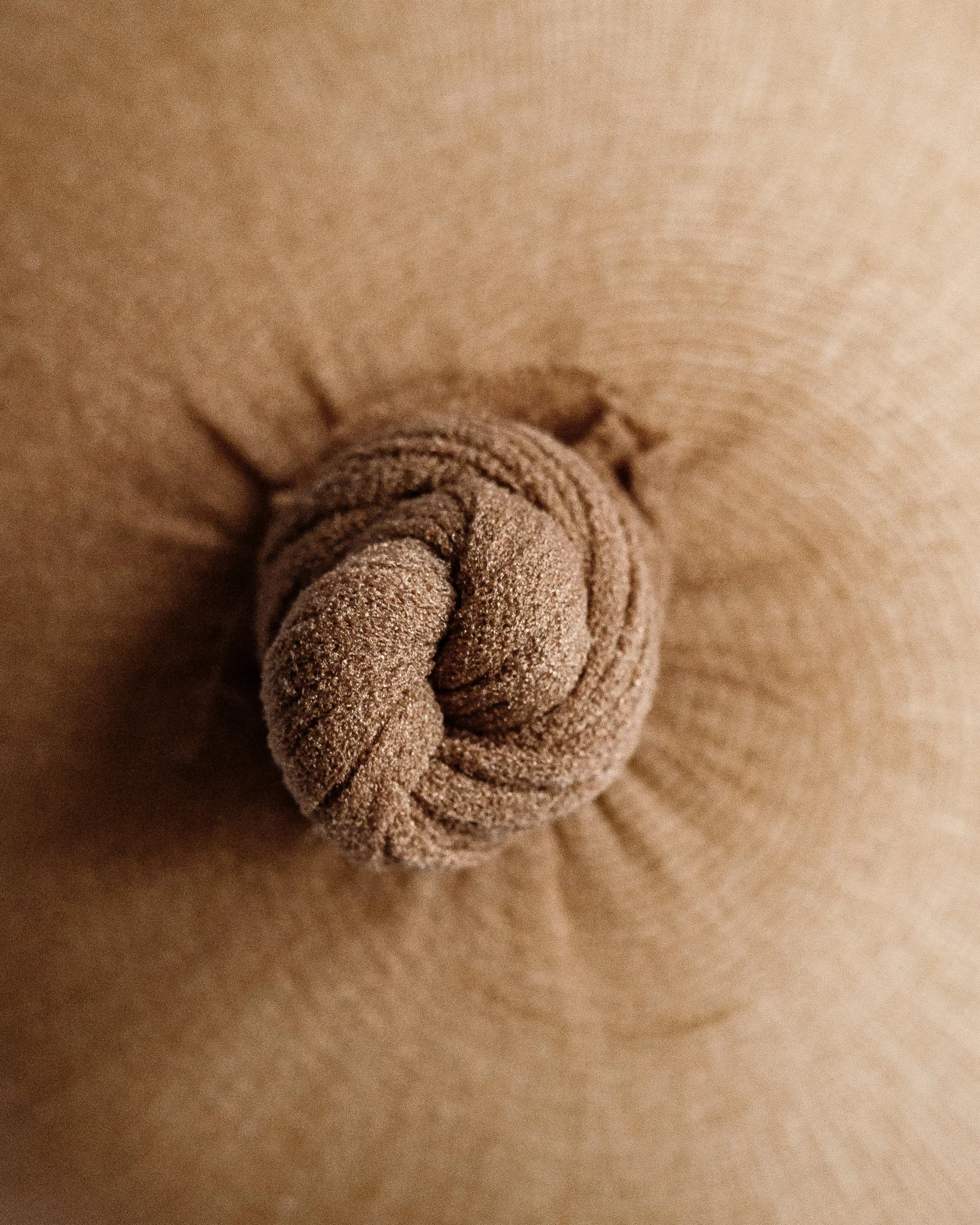 Close-up view of a ball of bread dough twisted in a pair of nylon stockings.