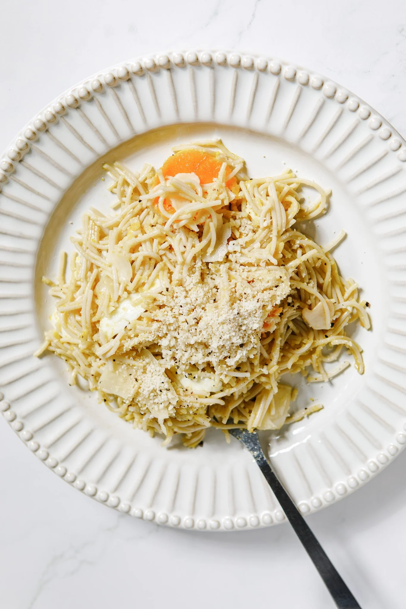 Thin spaghetti with fried egg and grated Parmesan cheese.