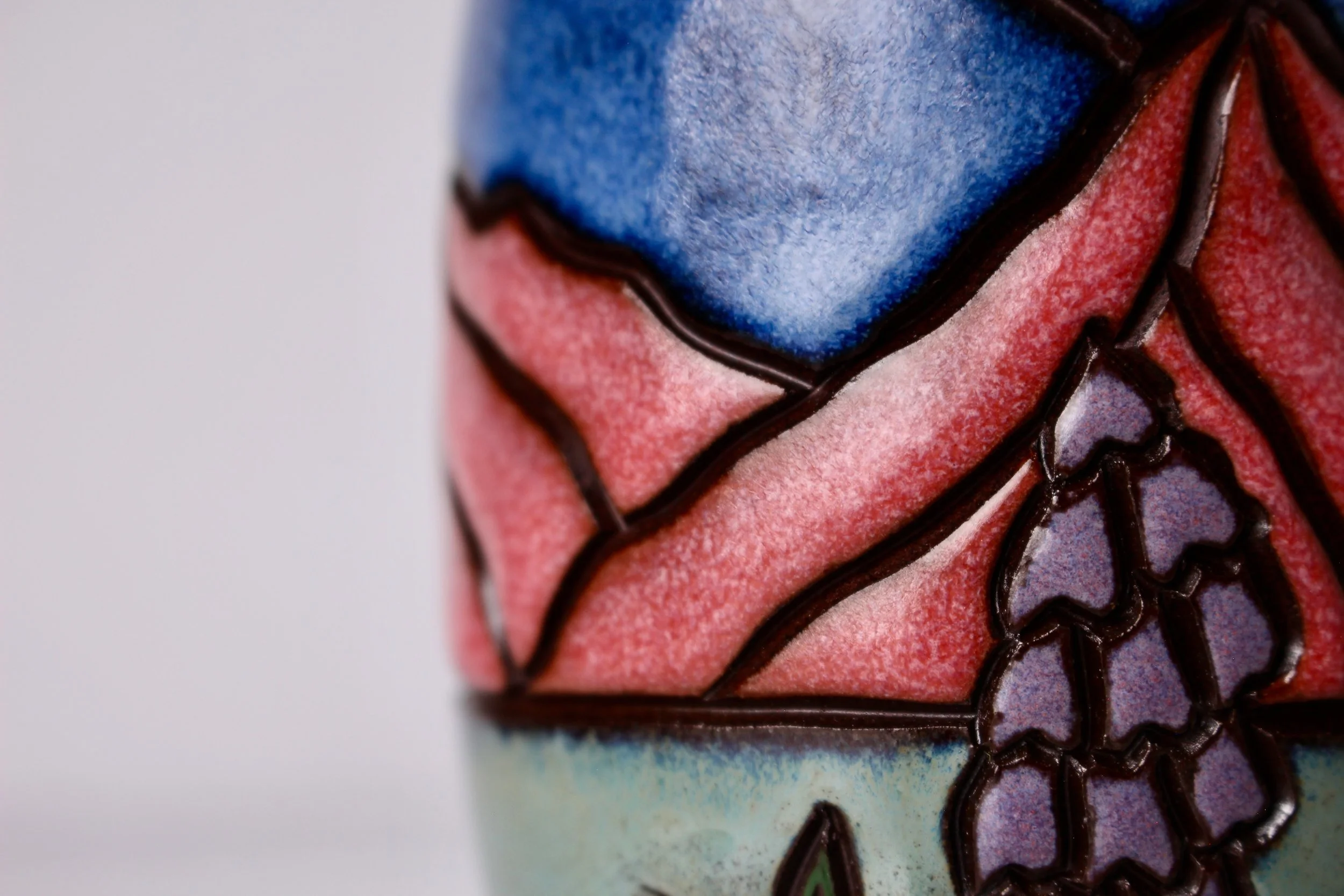 Close-up of a ceramics oil cruet with colorful blue, pink, green, and purple glazes