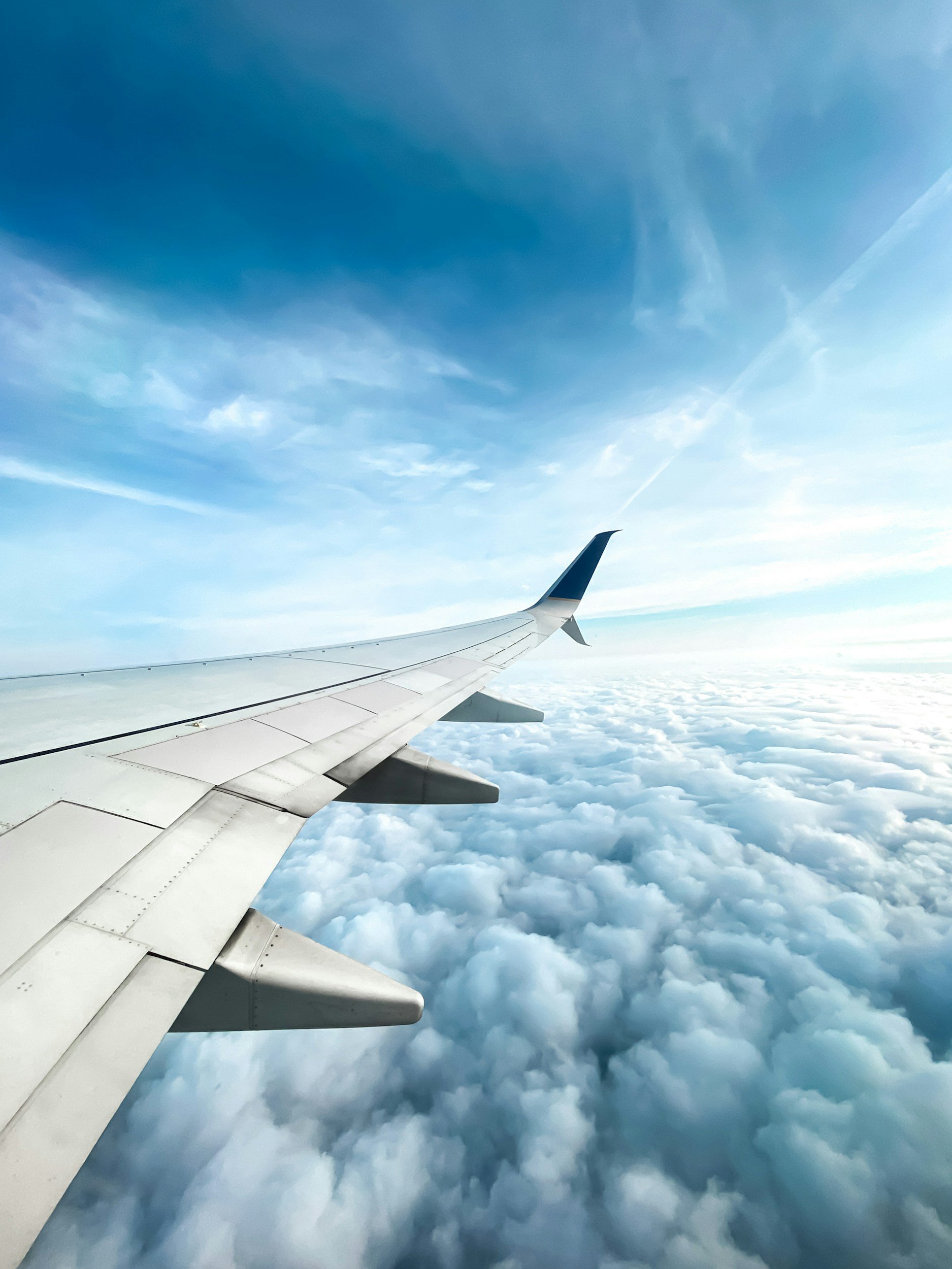 View from an airplane window showing a wing and a cloudy sky.
