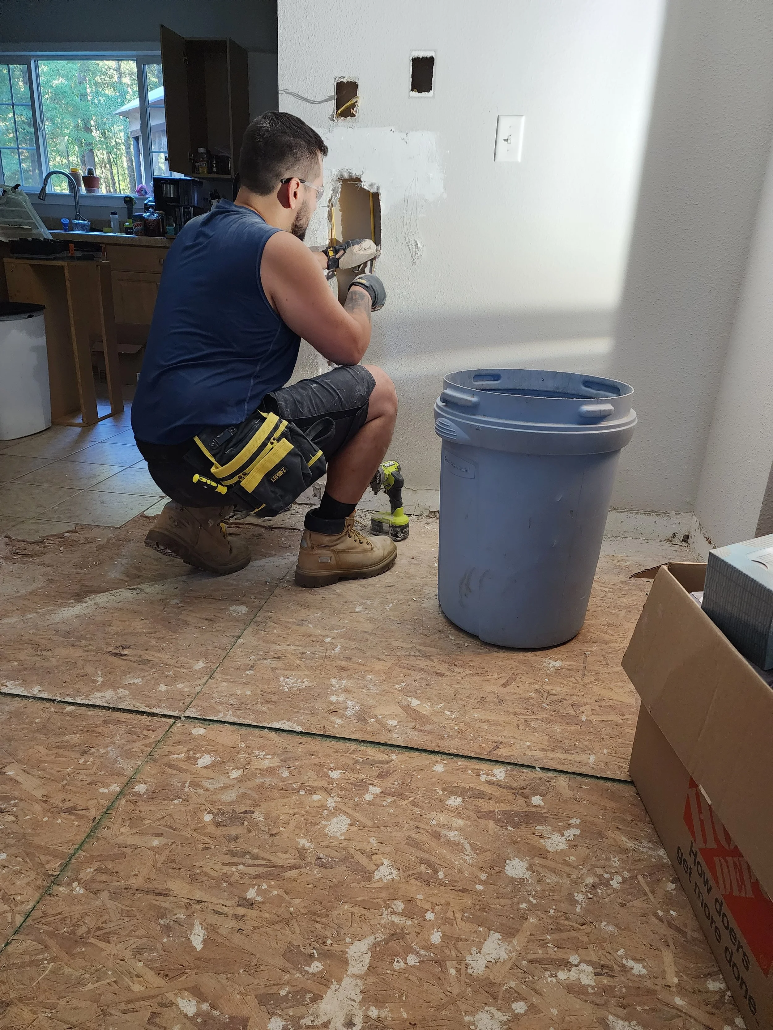 Man kneeling on the floor working on electrical wires.